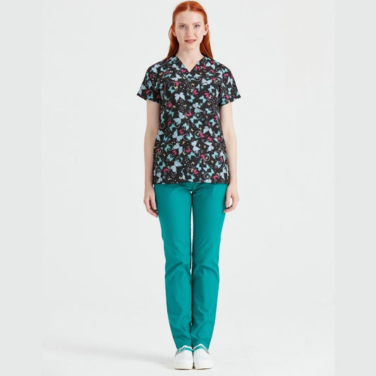 Asistenta imbracata intr-o uniforma medicala compusa dintr-o bluza cu model Fluturi Turquoise si pantaloni lungi verzi chirurgical